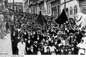 Imagens de uma das ruas de São Paulo tomada de trabalhadores com bandeiras na greve geral de 1917